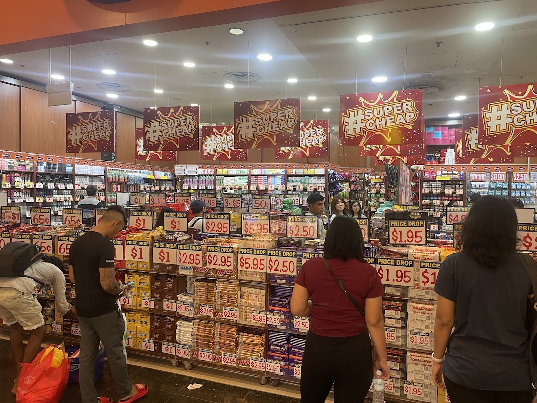 Customers browse aisles filled with discounted snacks and goods under 'Super Cheap' banners at Valu.