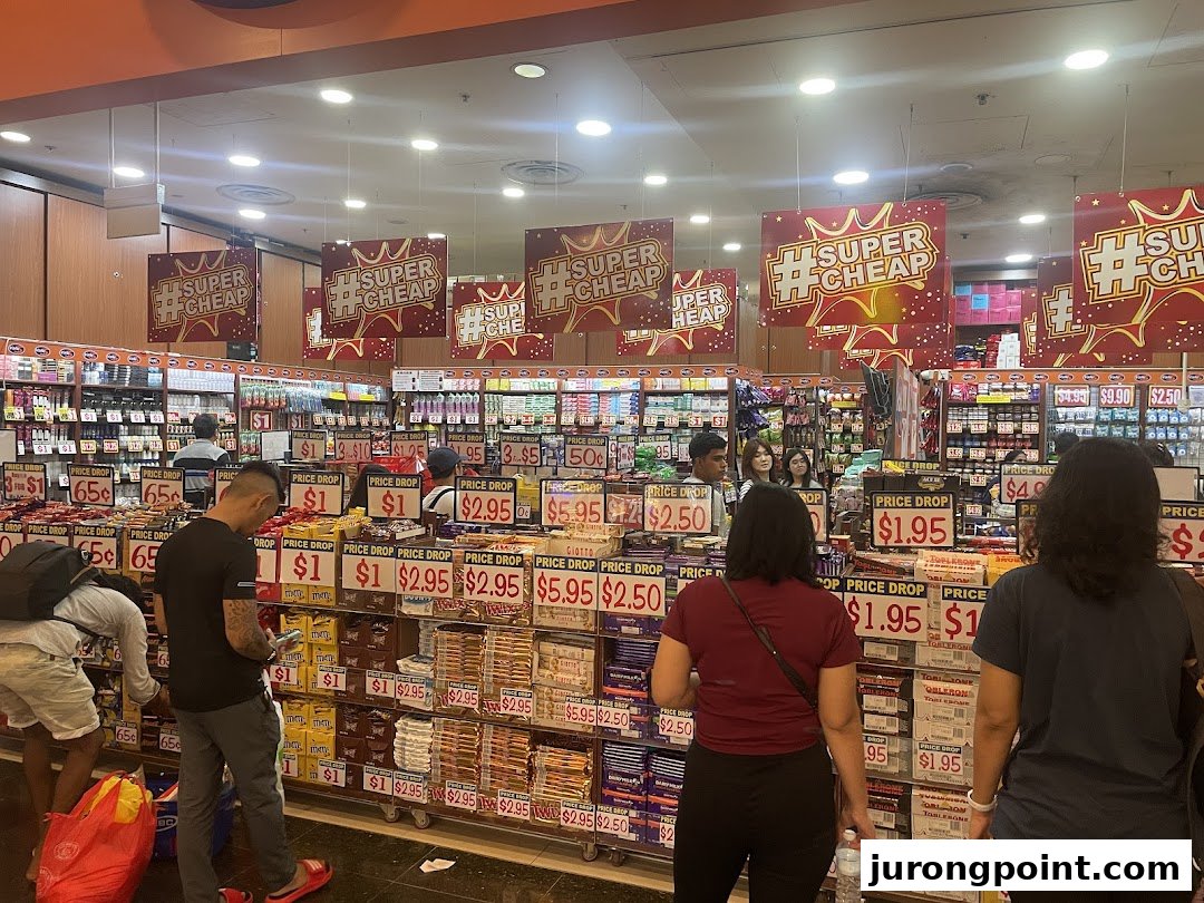 Customers browse aisles filled with discounted snacks and goods under 'Super Cheap' banners at Valu.