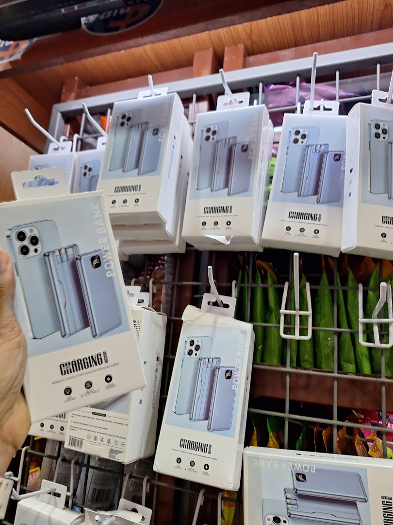 A display of packaged power banks and phone accessories hanging on a retail rack inside Valu.