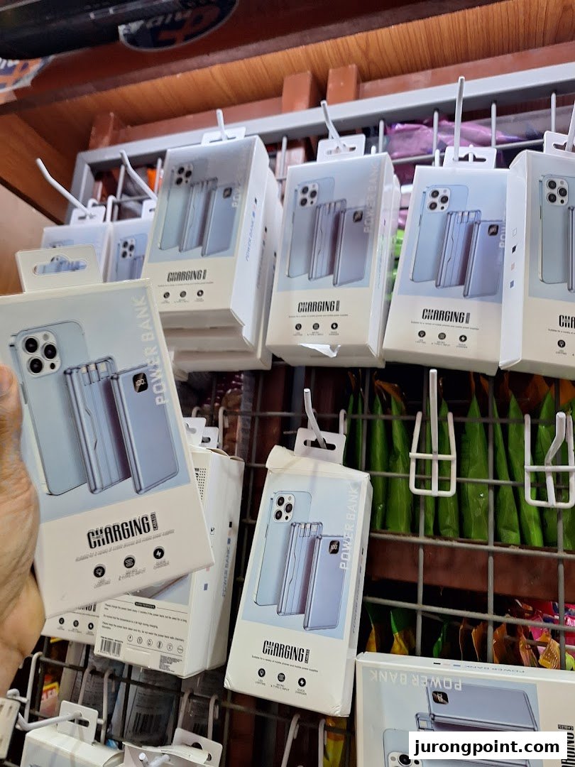 A display of packaged power banks and phone accessories hanging on a retail rack inside Valu.