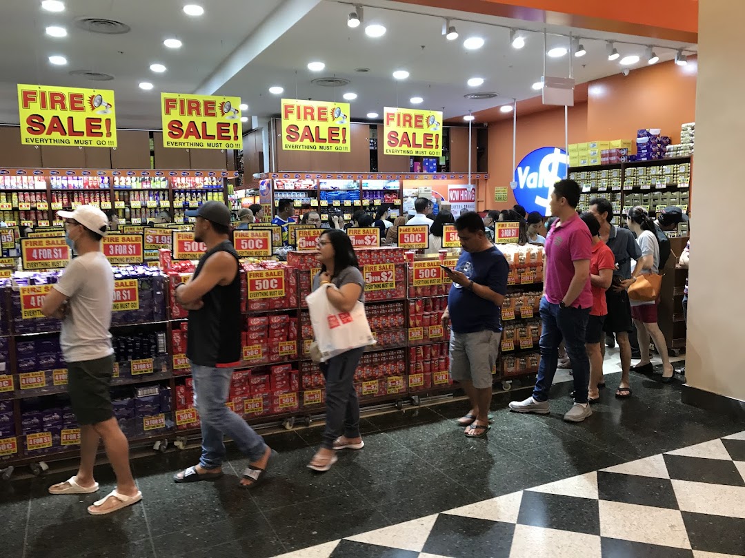 Customers queue at the entrance of Valu, a busy discount store featuring prominent 'Fire Sale' signs.