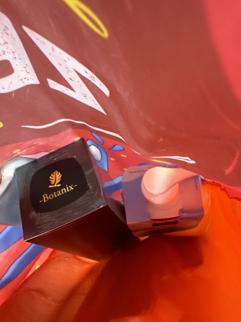 Two beauty products, including one labeled 'Botanix', inside a red shopping bag.