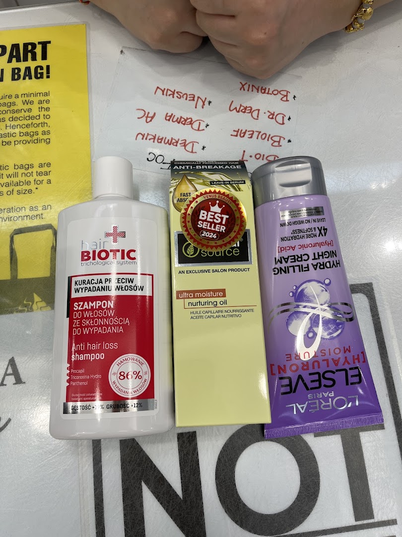 Close-up of various hair and beauty products, including shampoo, hair oil, and night cream, on a counter.