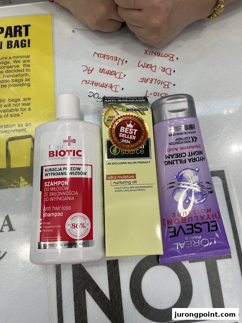 Close-up of various hair and beauty products, including shampoo, hair oil, and night cream, on a counter.