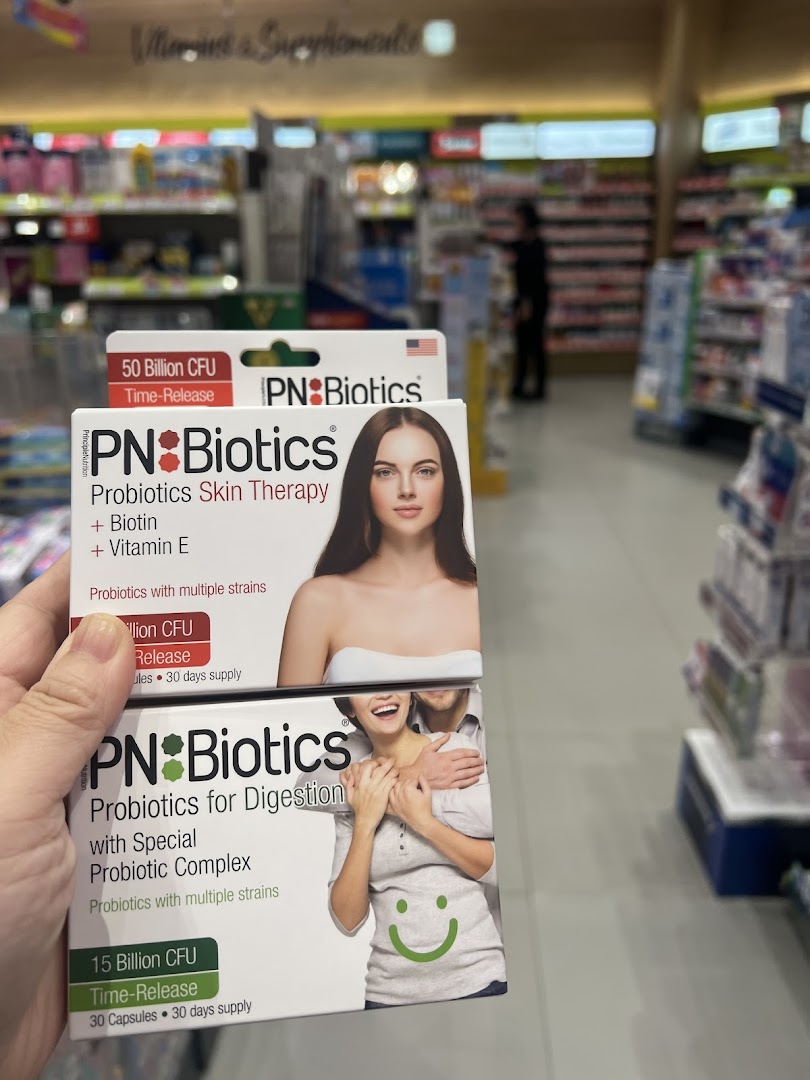 Hand holding two PN Biotics probiotic boxes inside a Watsons pharmacy.