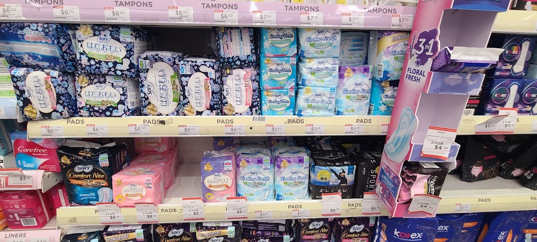 A well-stocked shelf display of feminine hygiene products, including pads and tampons, in a retail store.