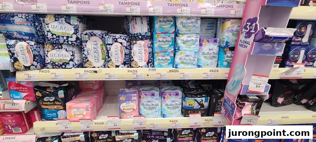 A well-stocked shelf display of feminine hygiene products, including pads and tampons, in a retail store.