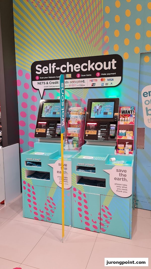 Two Watsons self-checkout kiosks with clear instructions and payment options in a brightly decorated area.