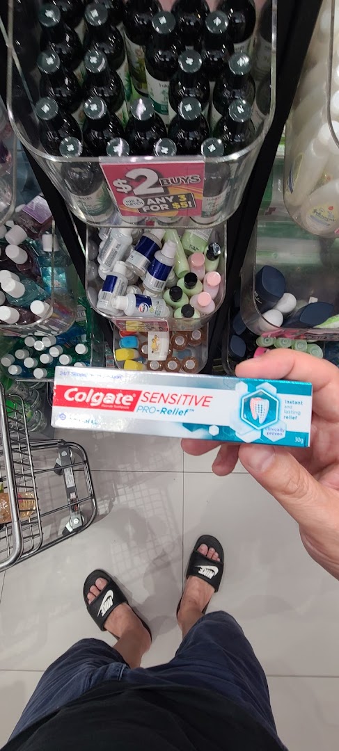 A person holds Colgate Sensitive Pro-Relief toothpaste inside a Watsons store, showcasing various health and beauty products.