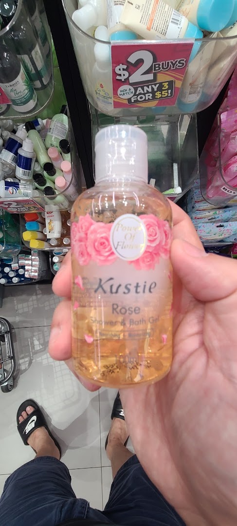 A hand holds a Kustie Rose Shower & Bath Gel bottle inside a Watsons store, showcasing a promotional offer.