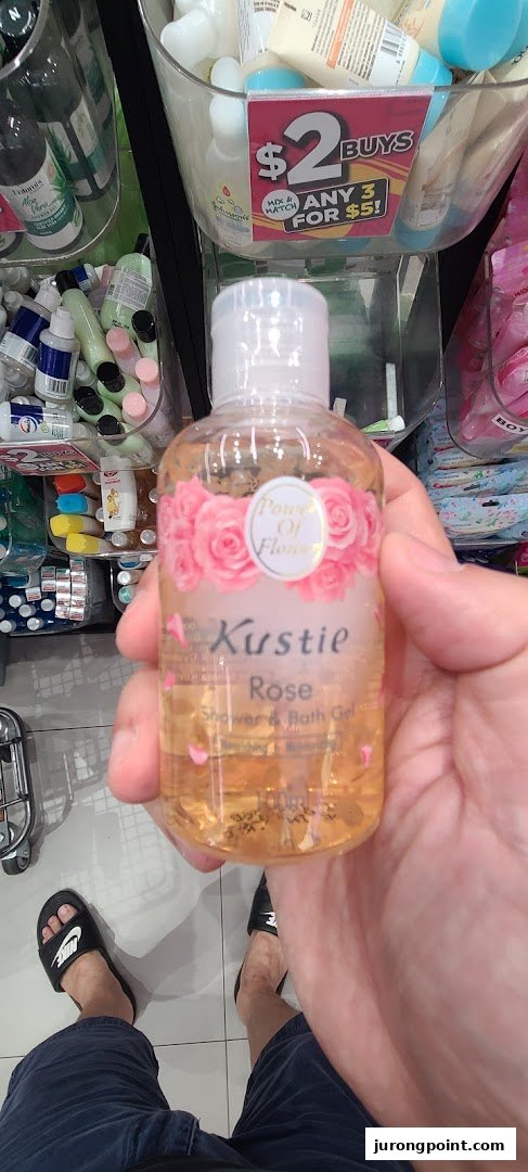 A hand holds a Kustie Rose Shower & Bath Gel bottle inside a Watsons store, showcasing a promotional offer.