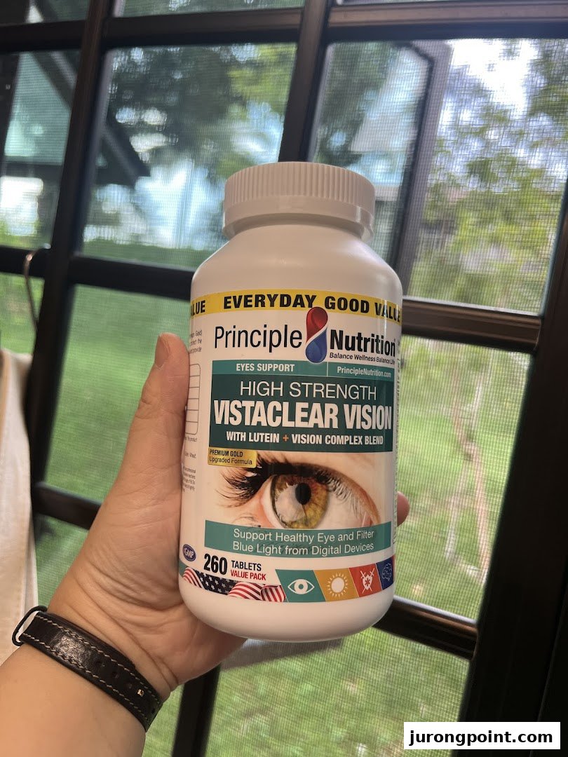 A hand holds a bottle of Principle Nutrition Vistaclear Vision eye support supplements.