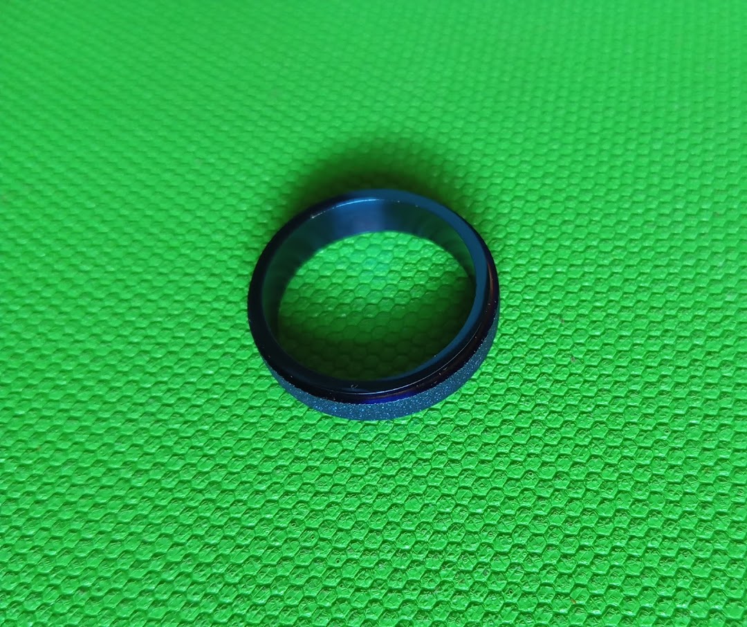 A blue and black ring with a textured band on a vibrant green background.