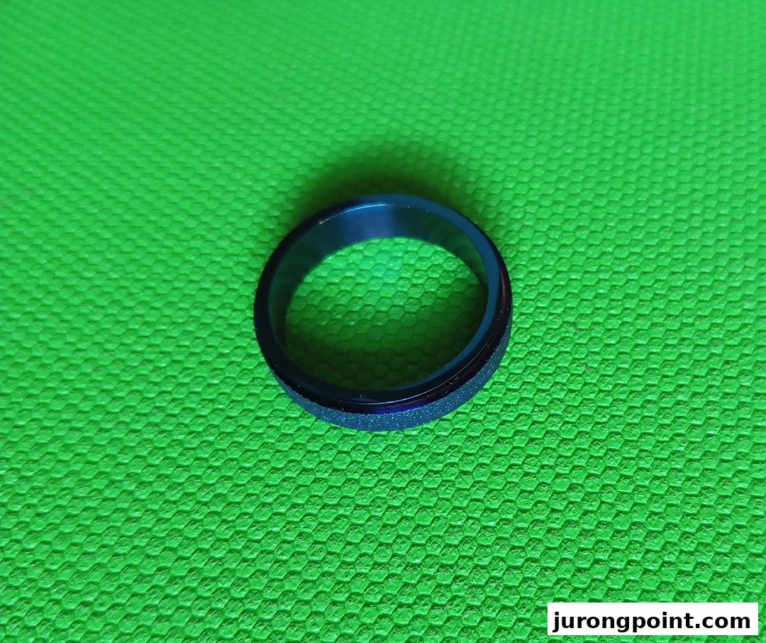 A blue and black ring with a textured band on a vibrant green background.