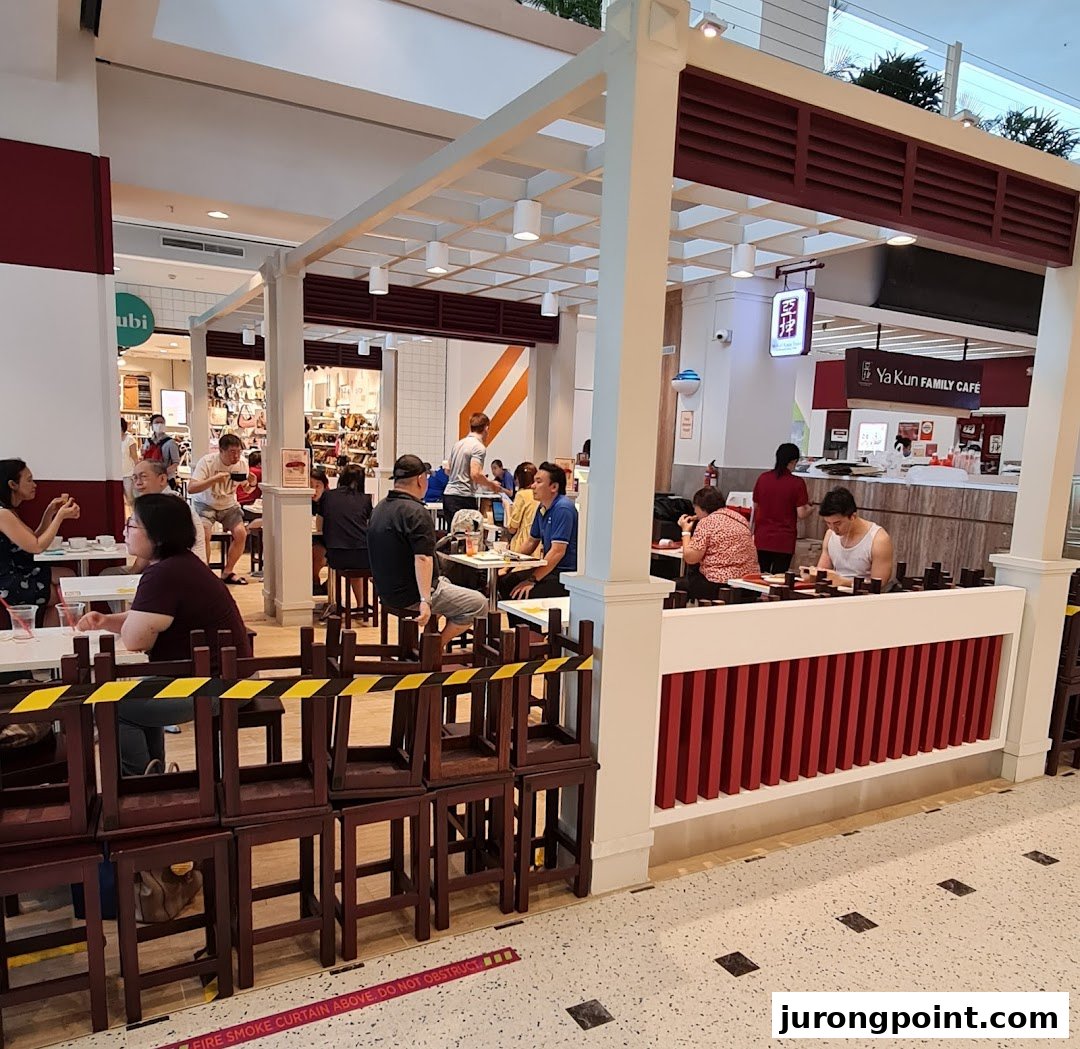 Customers enjoy traditional Singaporean breakfast and snacks in a bustling Ya Kun Family Cafe setting.