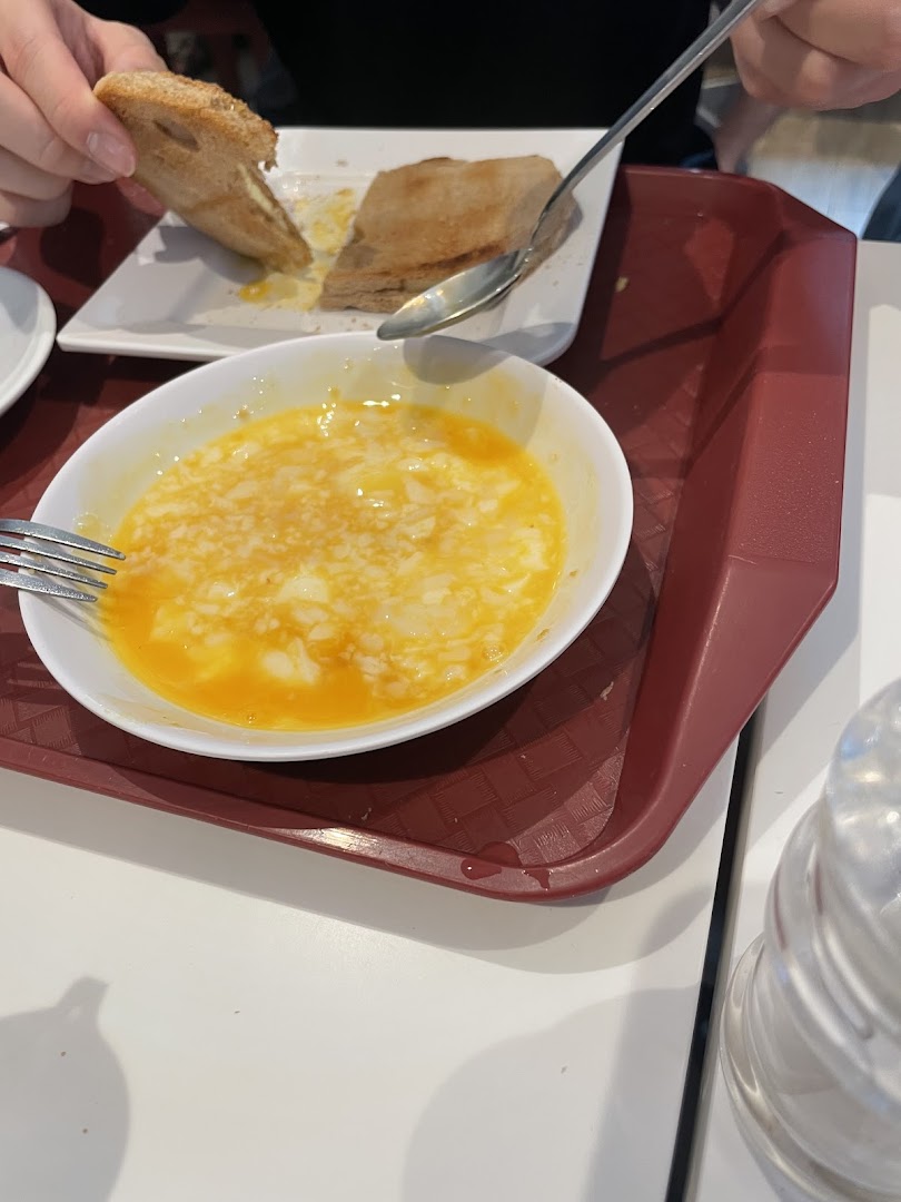 A close-up of a traditional Singaporean breakfast featuring soft-boiled eggs and kaya toast.