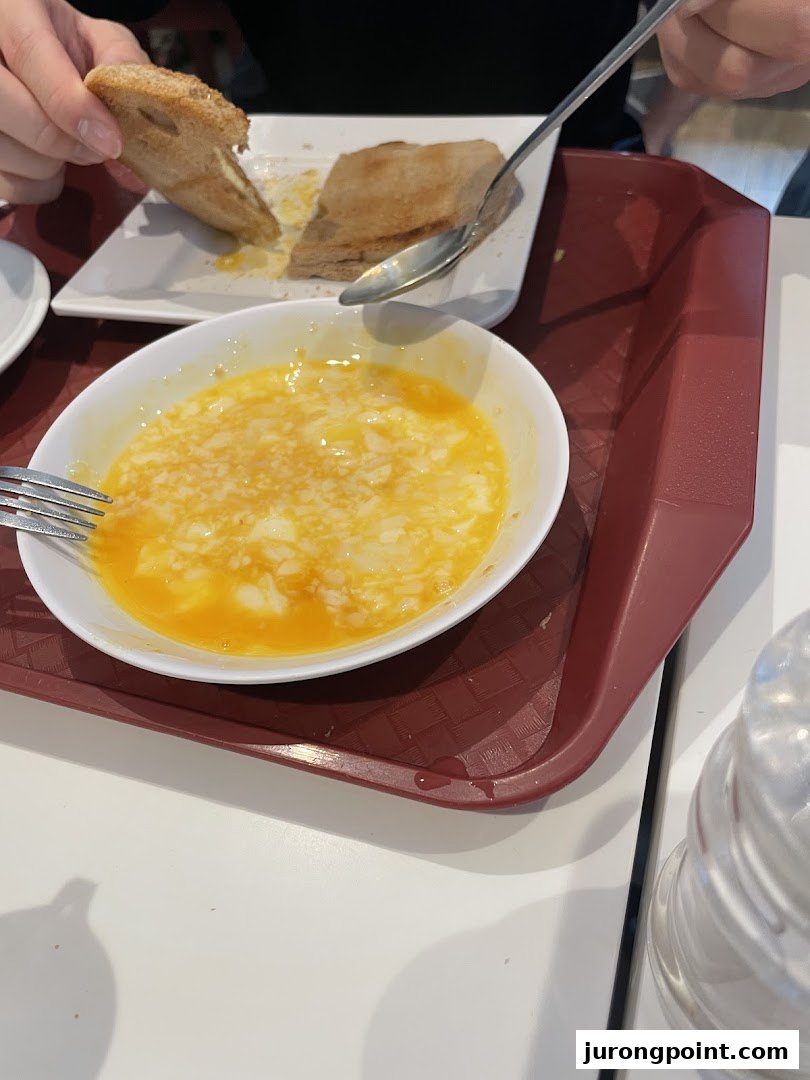 A close-up of a traditional Singaporean breakfast featuring soft-boiled eggs and kaya toast.