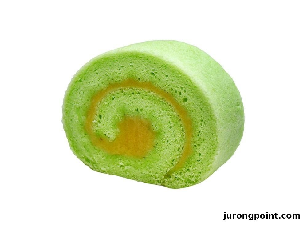 A vibrant green pandan cake roll with a golden-yellow filling, isolated on a white background.