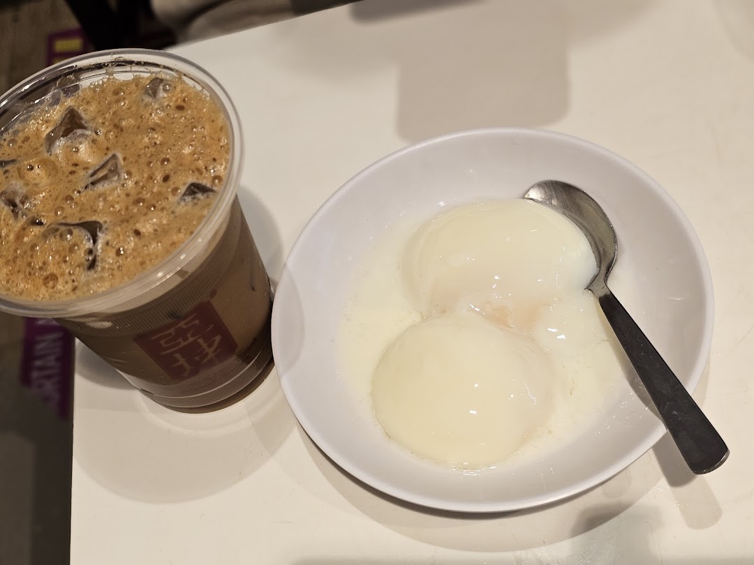 A classic Ya Kun breakfast set featuring soft-boiled eggs and an iced beverage.