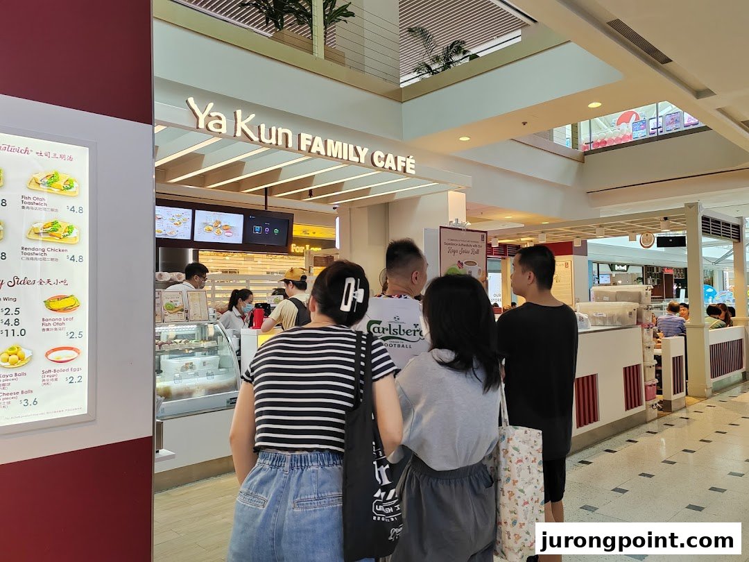 Customers queueing at the counter of Ya Kun Family Cafe, with a menu board visible on the left.