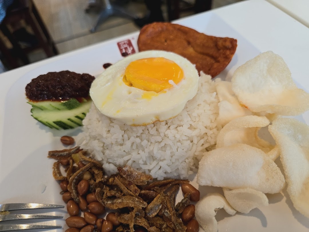 A delicious plate of Nasi Lemak with rice, egg, sambal, anchovies, peanuts, and crackers.