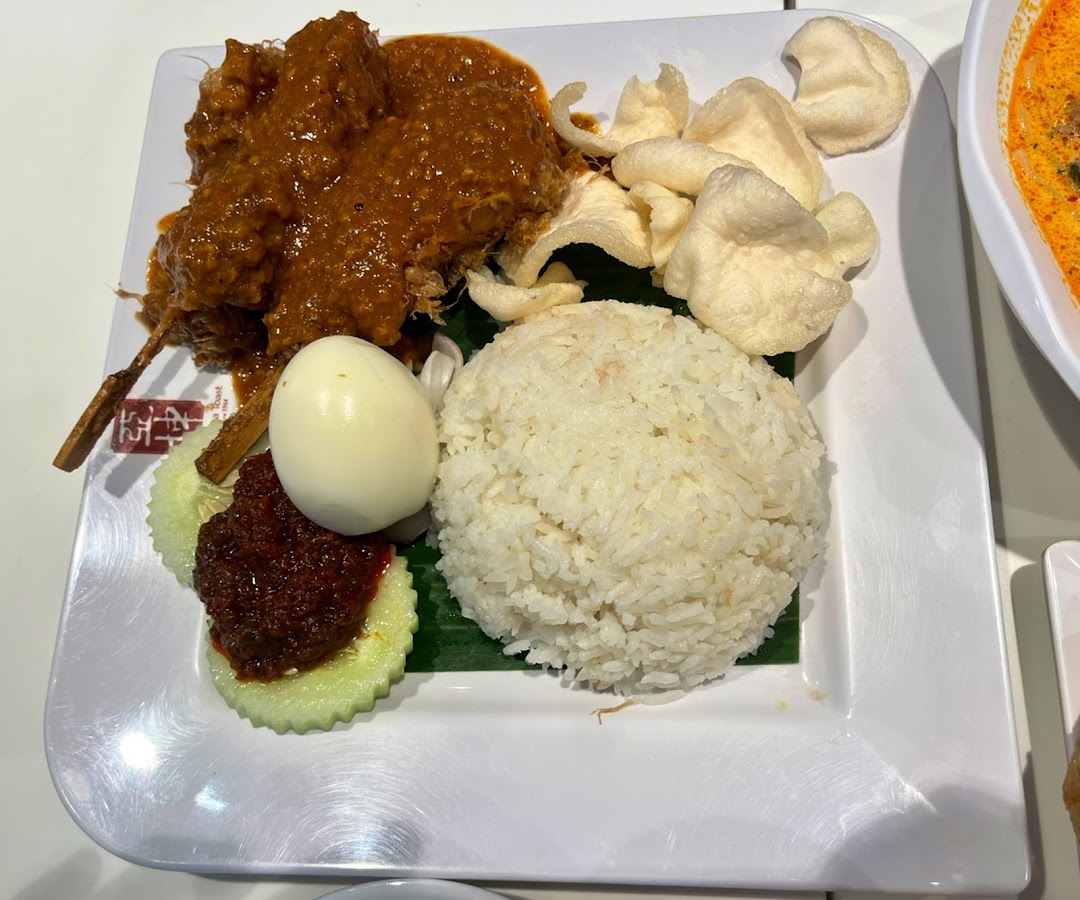 A delicious plate of Nasi Lemak with chicken rendang, fragrant rice, egg, sambal, and crispy keropok.