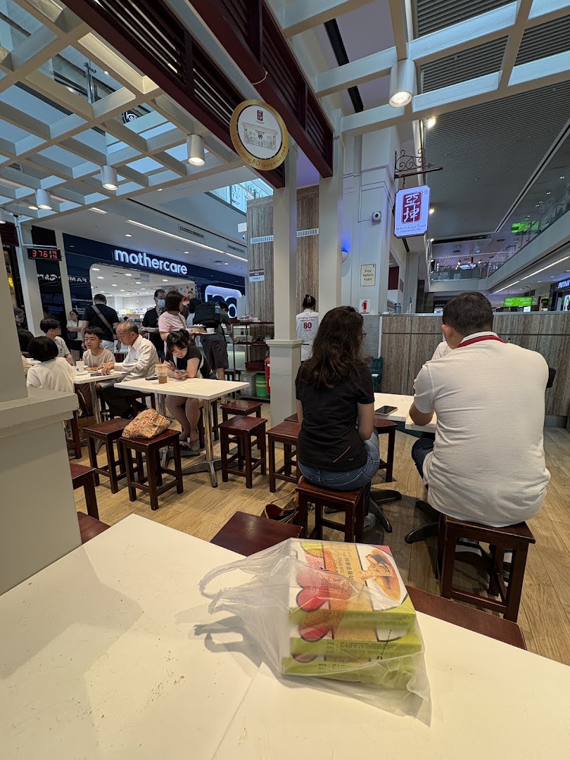 Customers enjoy traditional kaya toast and coffee at Ya Kun Family Cafe, located within a bustling shopping mall.
