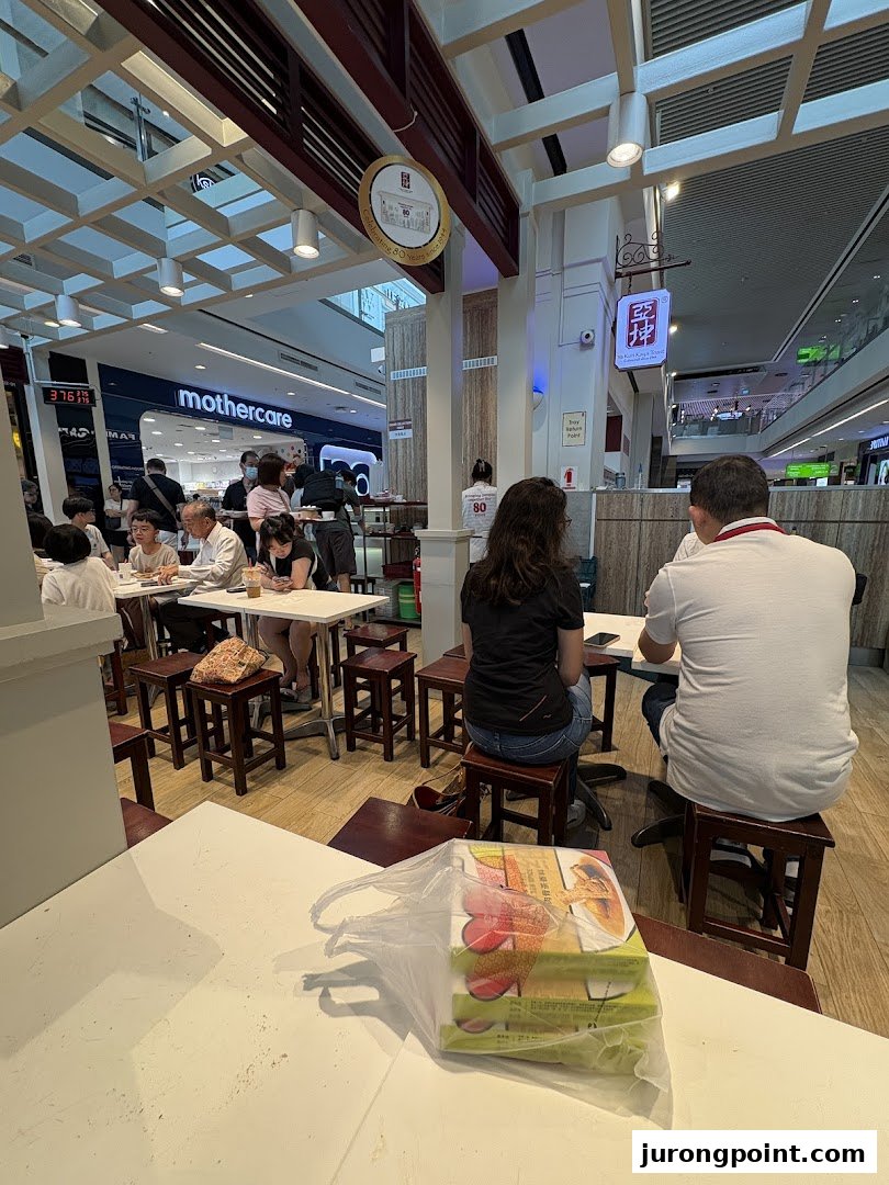 Customers enjoy traditional kaya toast and coffee at Ya Kun Family Cafe, located within a bustling shopping mall.