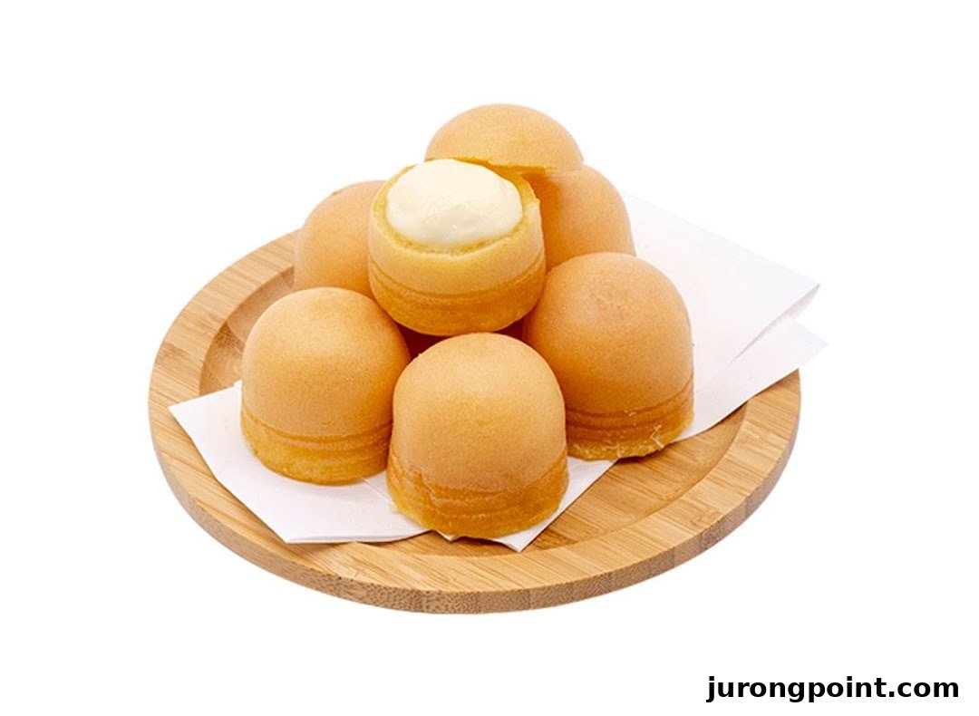 A wooden plate holds several golden-brown, dome-shaped pastries, one revealing a creamy white filling.