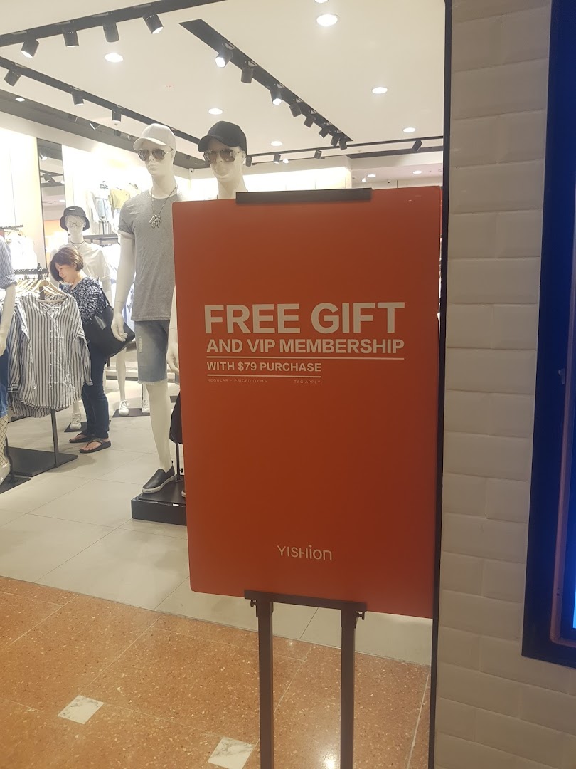 A promotional sign for YISHION inside the store, featuring mannequins and clothing.