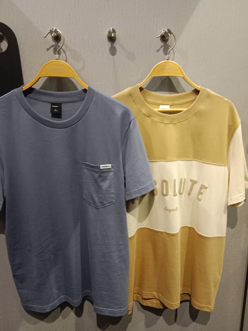 Two stylish t-shirts, one blue and one multi-colored, displayed on hangers in a retail store.