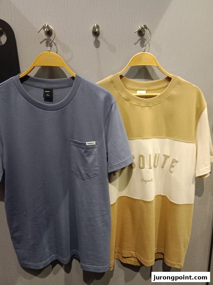 Two stylish t-shirts, one blue and one multi-colored, displayed on hangers in a retail store.