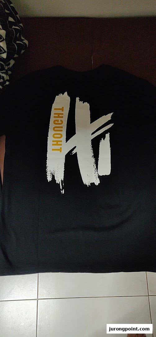 A black t-shirt featuring a white brushstroke design and the word 'THOUGHT' in gold.