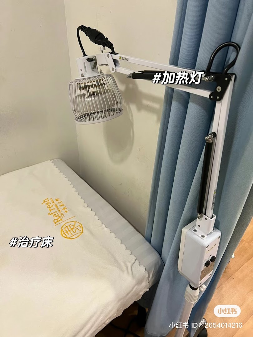 A treatment bed and heating lamp in a therapy room at Yong Kang TCM Clinic.