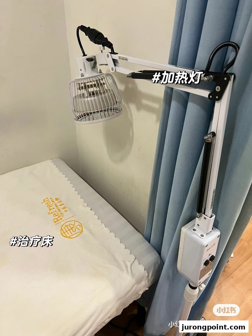 A treatment bed and heating lamp in a therapy room at Yong Kang TCM Clinic.