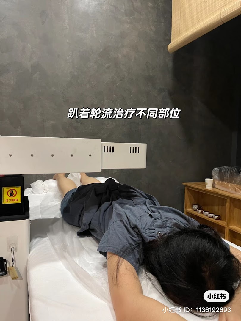 A person receives traditional Chinese medicine therapy on a treatment bed with an overhead device.