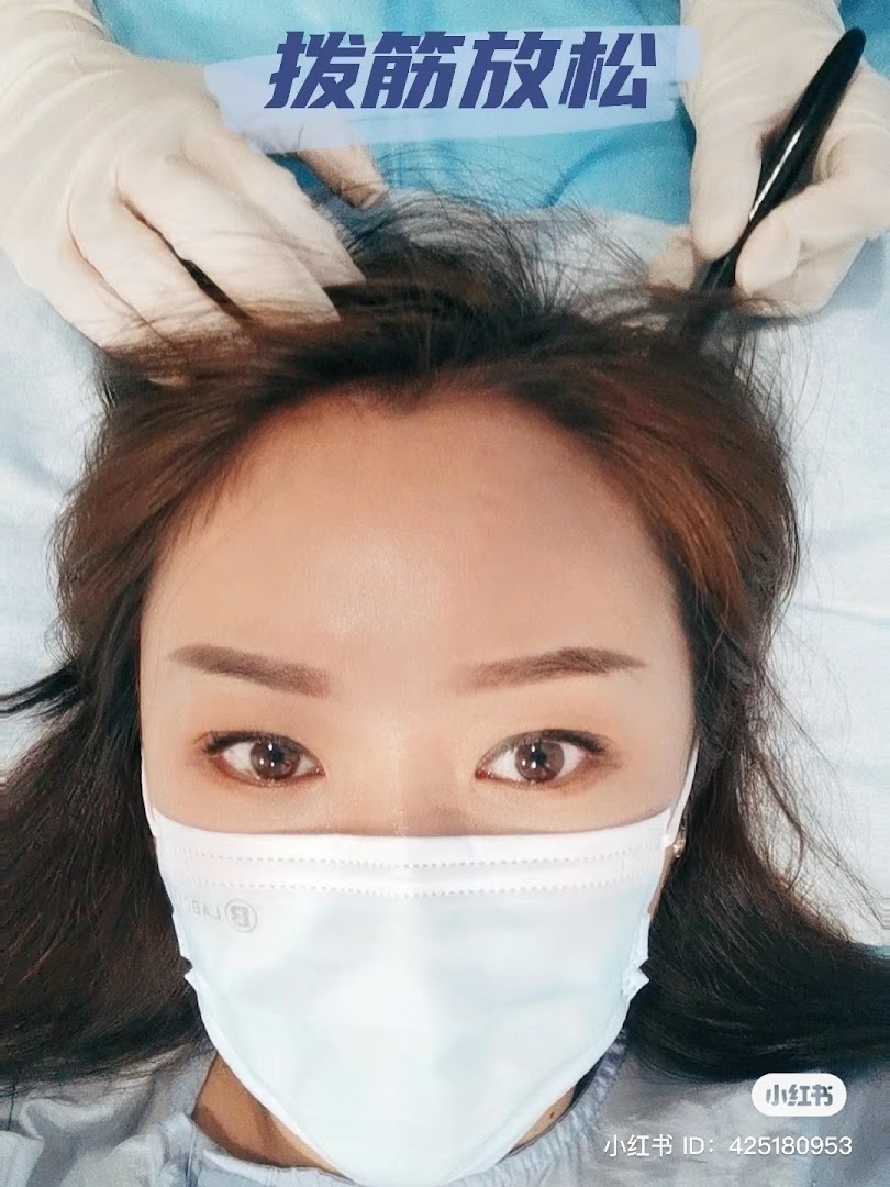 A client receives a relaxing head treatment from a gloved practitioner at Yong Kang TCM Clinic.