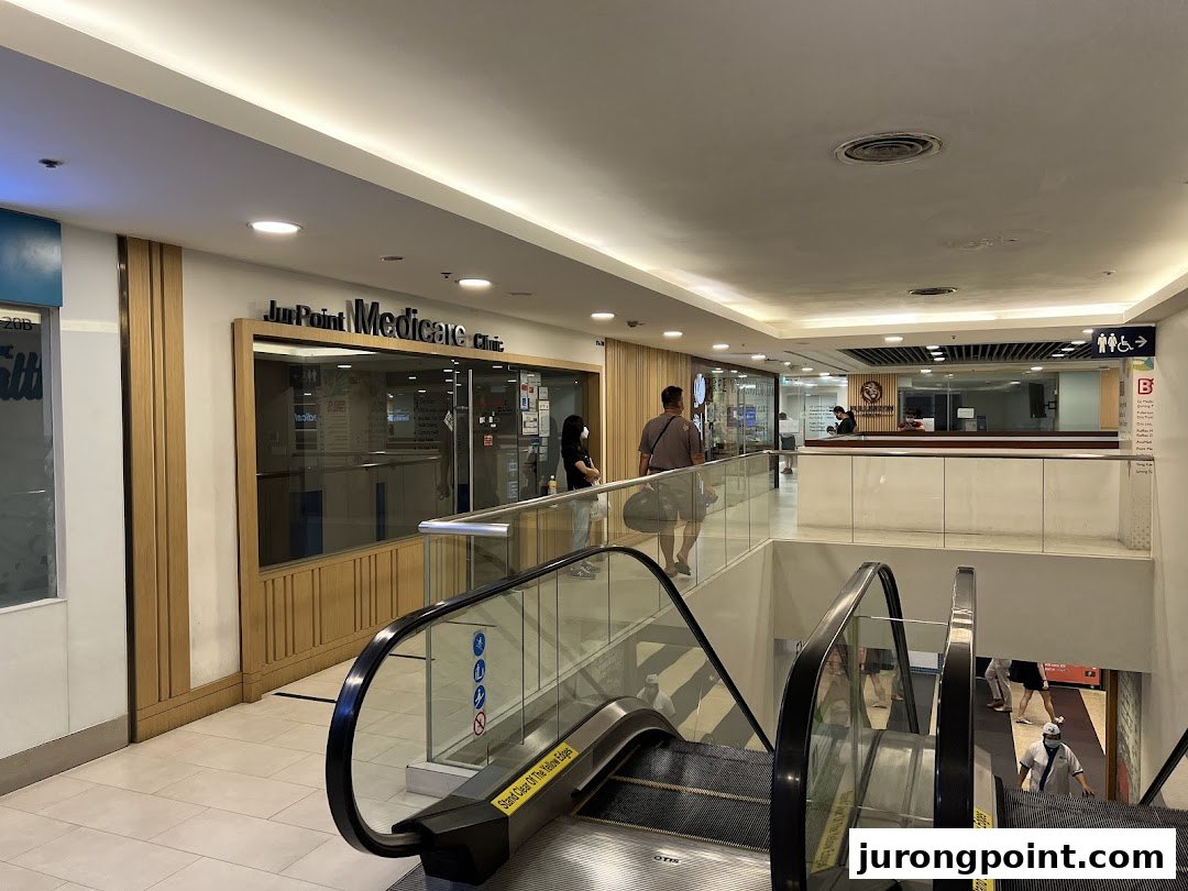 A view of a clinic entrance with escalators in a brightly lit shopping mall.