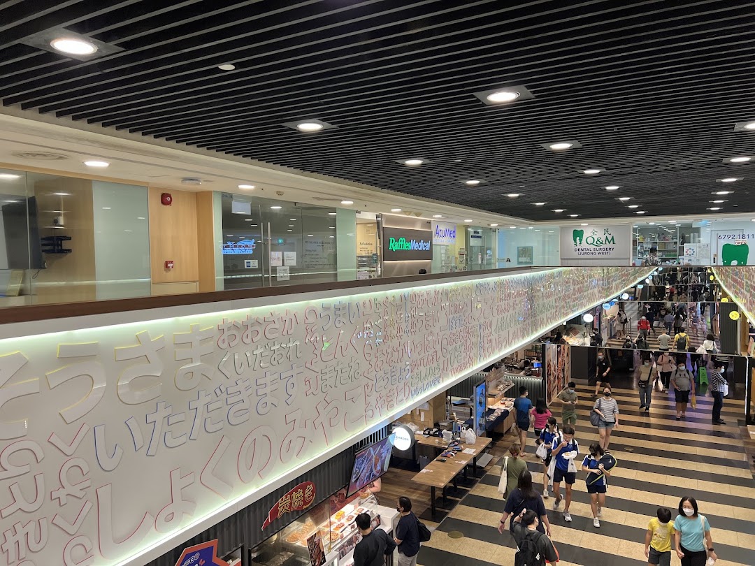 A bustling shopping mall interior featuring an upper level with various clinics and a lower level with shoppers.