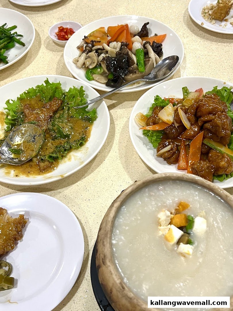 A table laden with various Chinese dishes, including a large bowl of porridge and stir-fries.