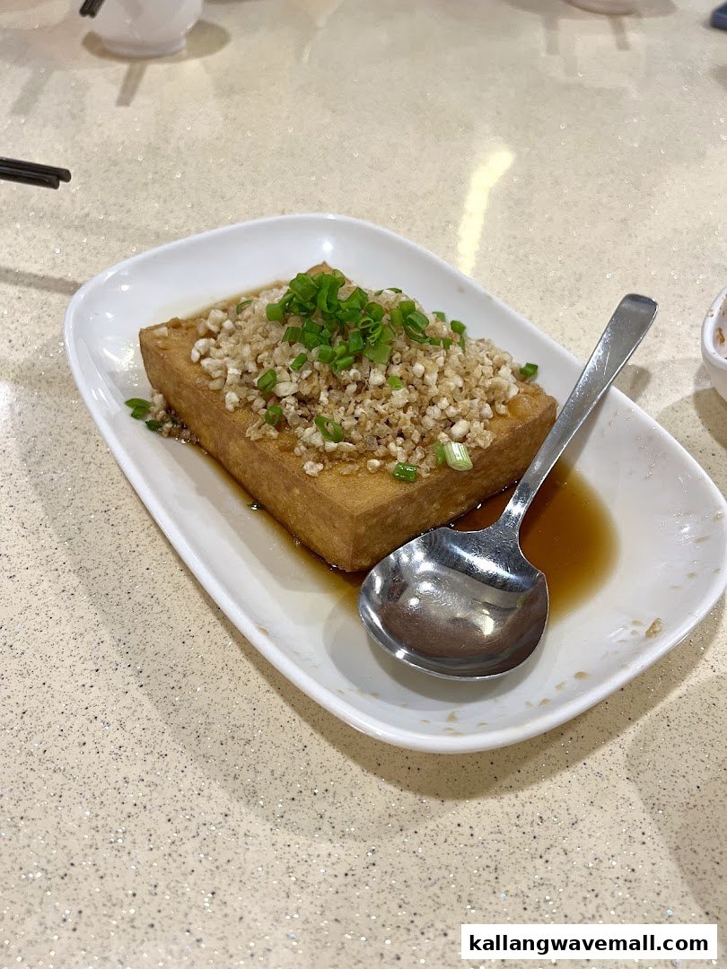 A plate of golden fried tofu topped with crispy garlic, green onions, and savory sauce.