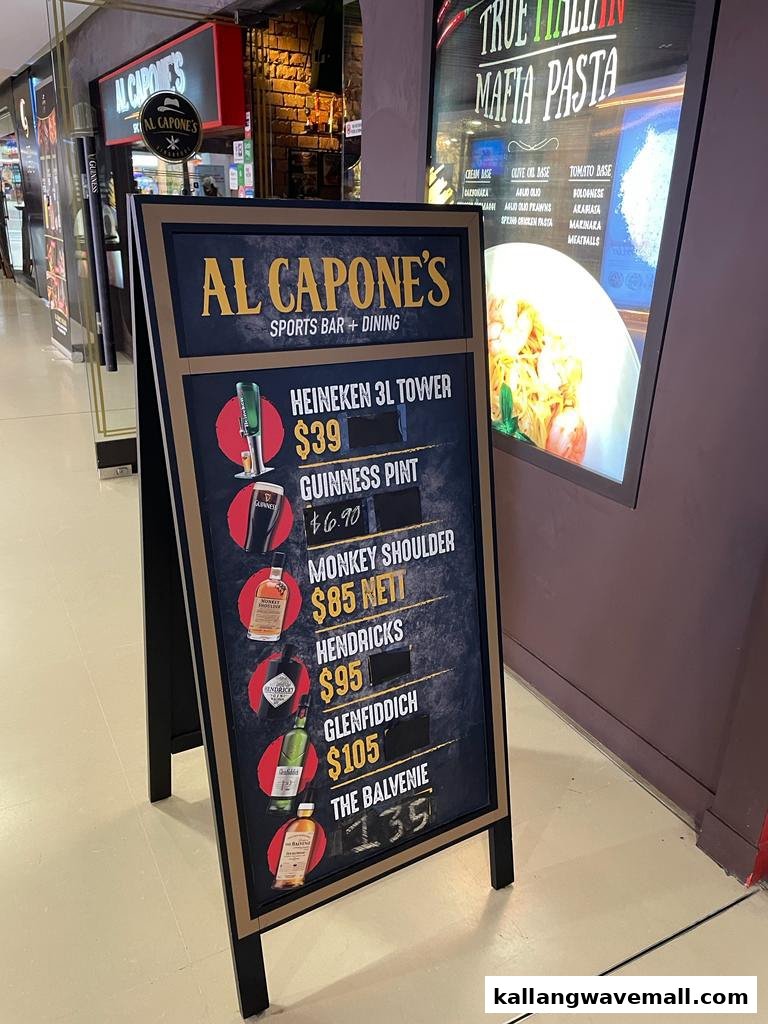 An A-frame sign displaying drink prices and a background poster showing pasta options for Al Capone's Sports Bar + Dining.