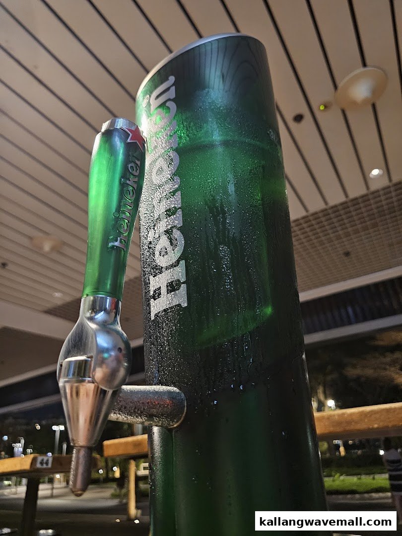 A close-up of a large, condensation-covered Heineken beer dispenser with a tap, ready for pouring.
