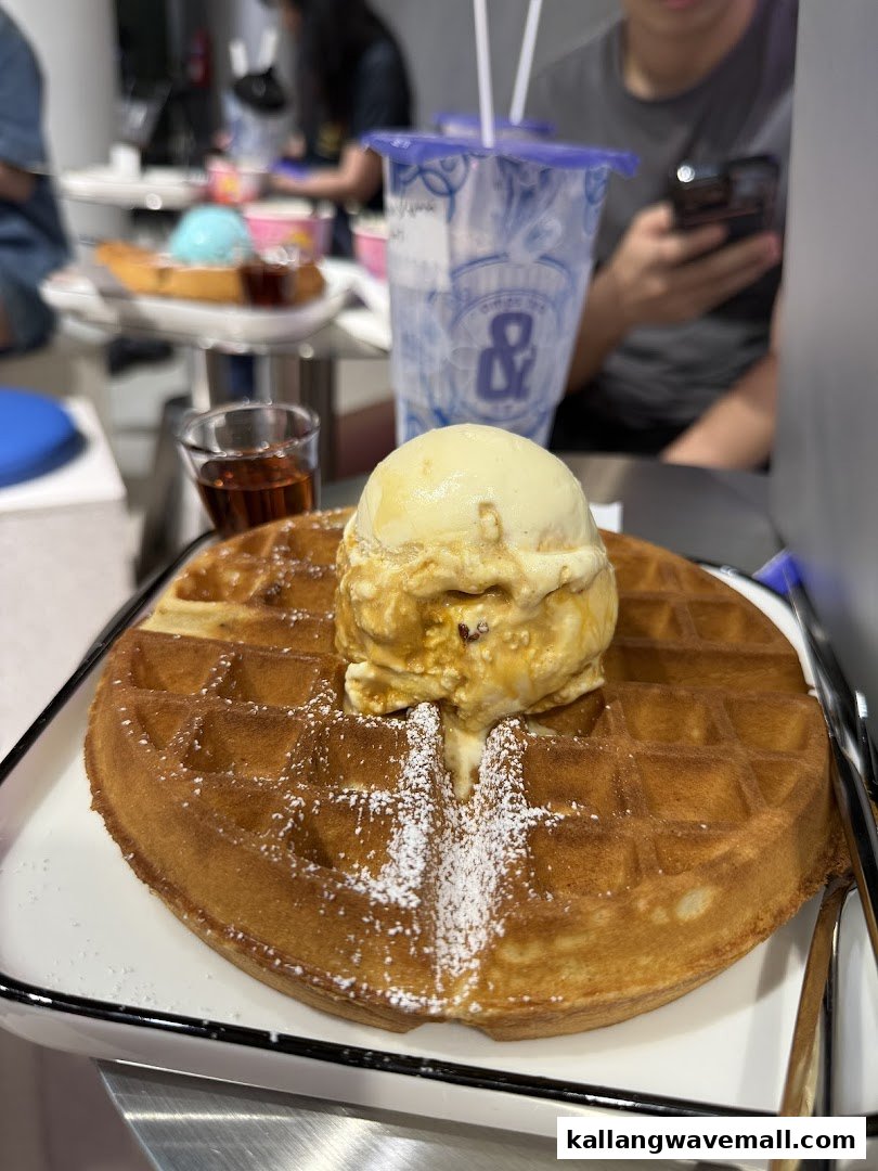 A delicious waffle topped with ice cream and powdered sugar, served with syrup and a drink.