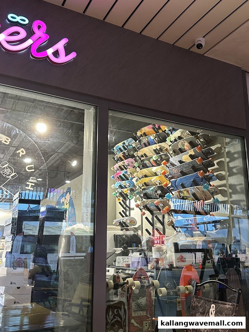 Shop exterior with a neon sign and a window display featuring numerous skateboards.