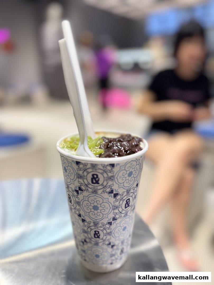 A close-up of a refreshing dessert in a branded cup, featuring green and dark toppings.