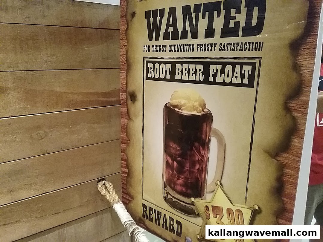 A 'Wanted' poster-style advertisement for a Root Beer Float with its price, displayed next to a wooden wall.