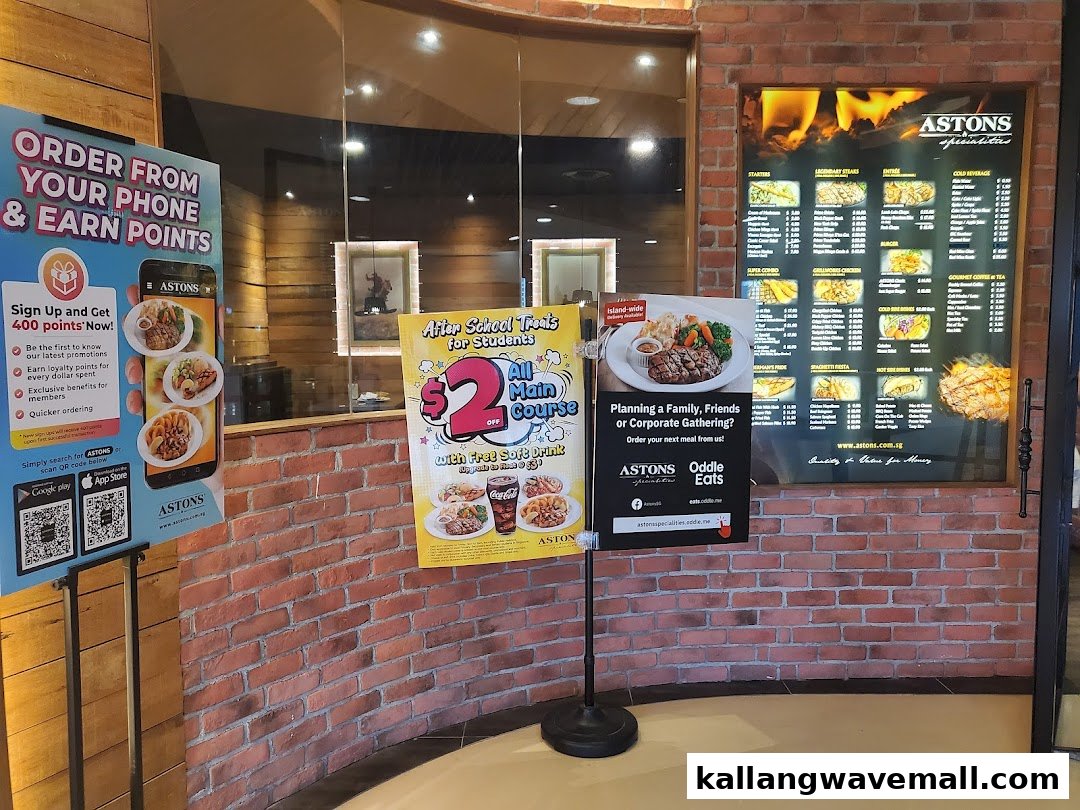 Entrance area of ASTONS Specialities, featuring promotional stands and a large menu board.