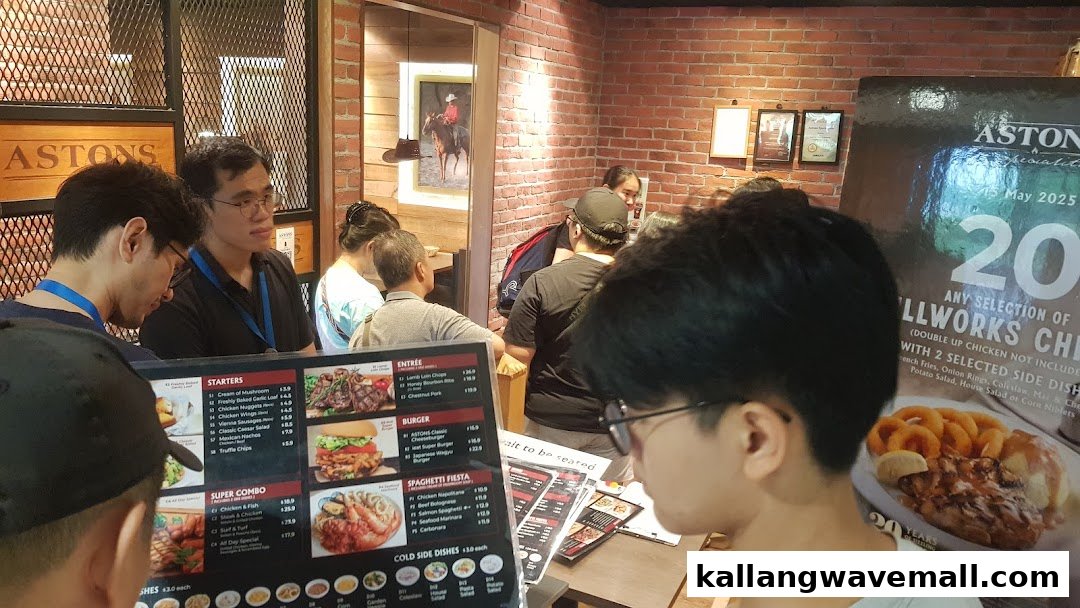 Customers view a large menu board and promotional poster at ASTONS Specialities, showcasing various dishes.