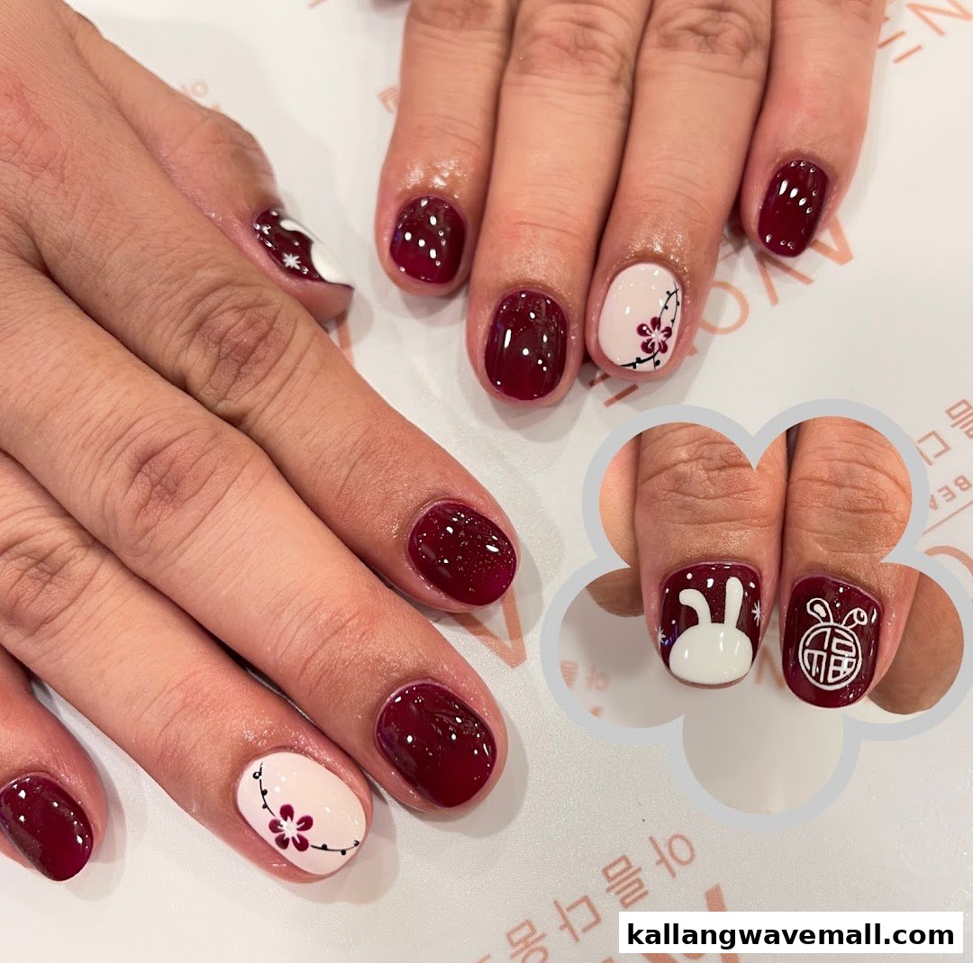 Close-up of hands showcasing elegant red and white nail art with floral and rabbit designs.